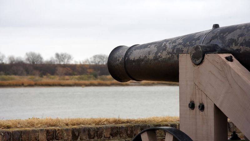 Historic black cannon overlooking a river at Old Fort Jackson in Savannah, Georgia.