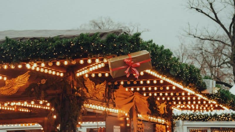 Market stall decorated with garlands, lights, and a gift box with a red bow.