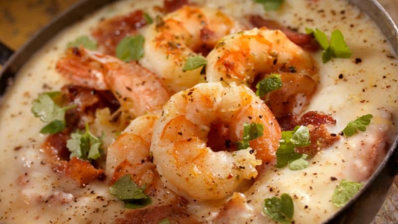 Shrimp and grits topped with bacon, herbs, and ground pepper.