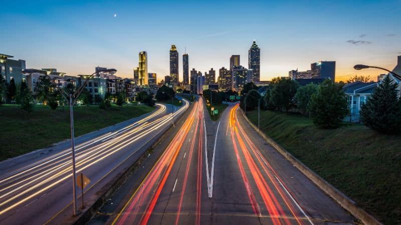 Atlanta skyline at dusk with highway light trails in the foreground.