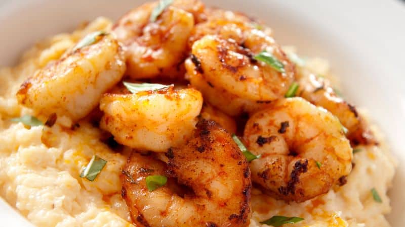 Grilled shrimp served over creamy grits with chopped herbs on top.