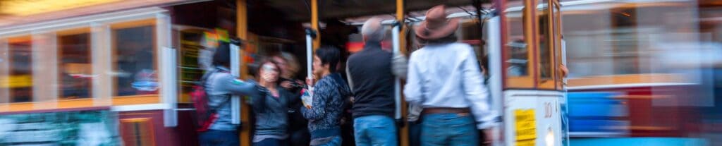 Passengers boarding a colorful trolley car in motion.