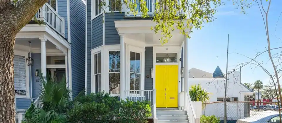 Historic blue Savannah home with a yellow front door and palm landscaping